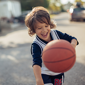 Niño jugando al aire libre con una pelota de baloncesto.