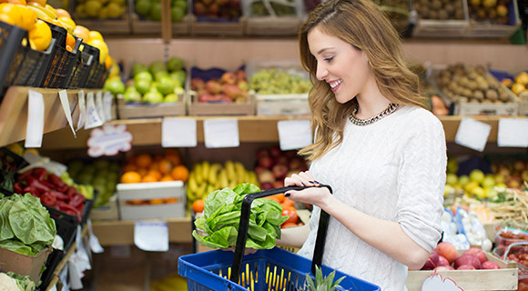 Woman at supermarket picking out vegetables to put in her shopping basket