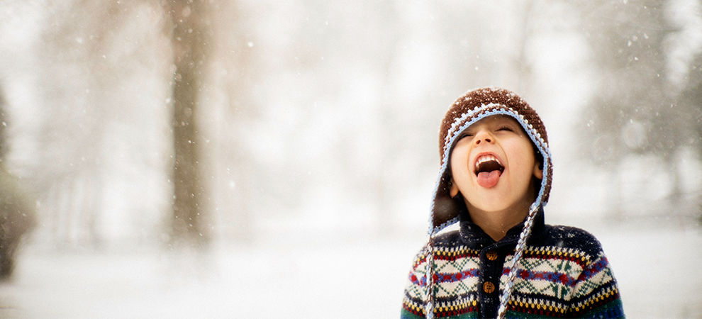 Niño pequeño tocando los copos de nieve con lengua